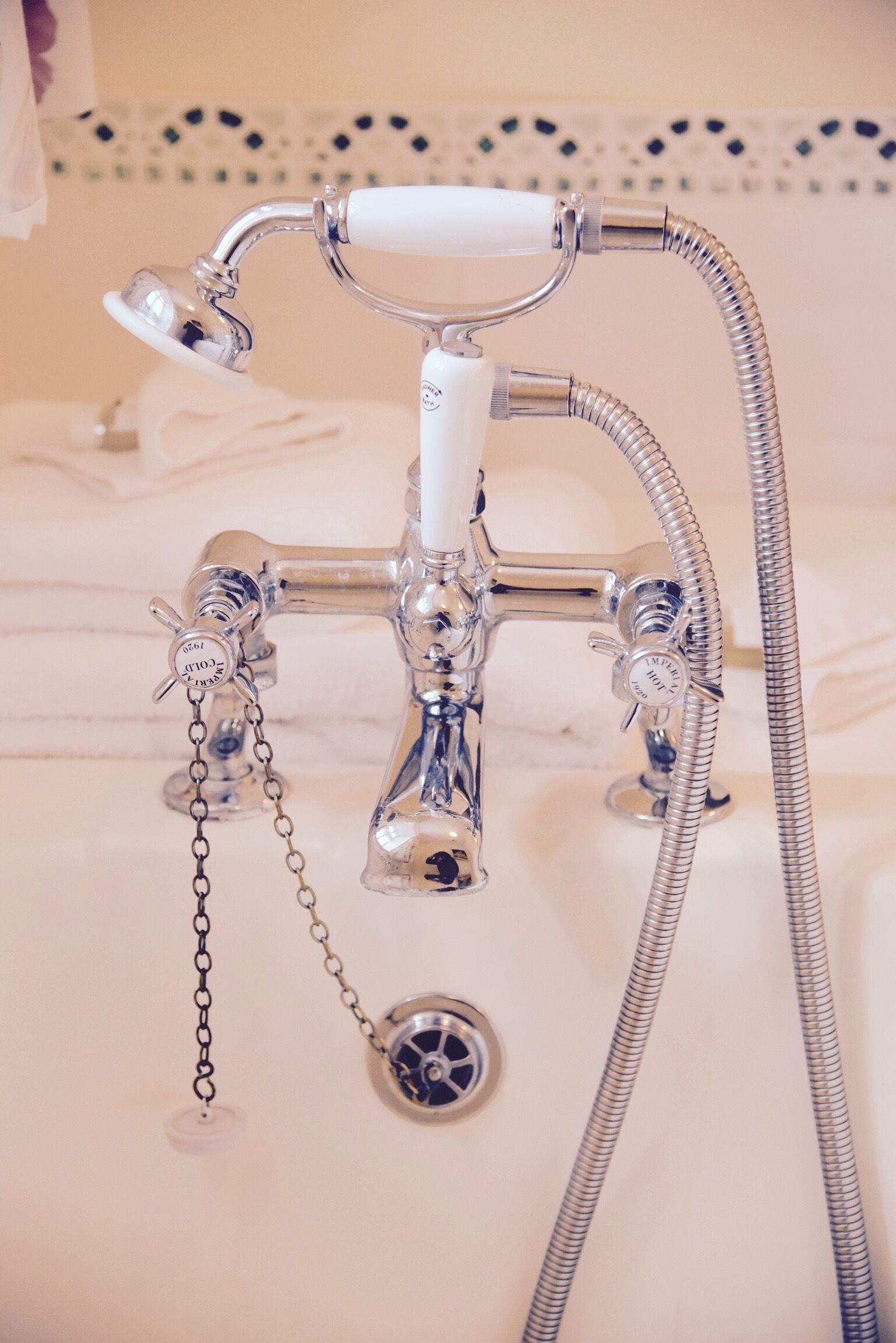 Une salle de bain dotée d’un robinet classique en chrome, d’une douchette et d’un drain fixé au mur.