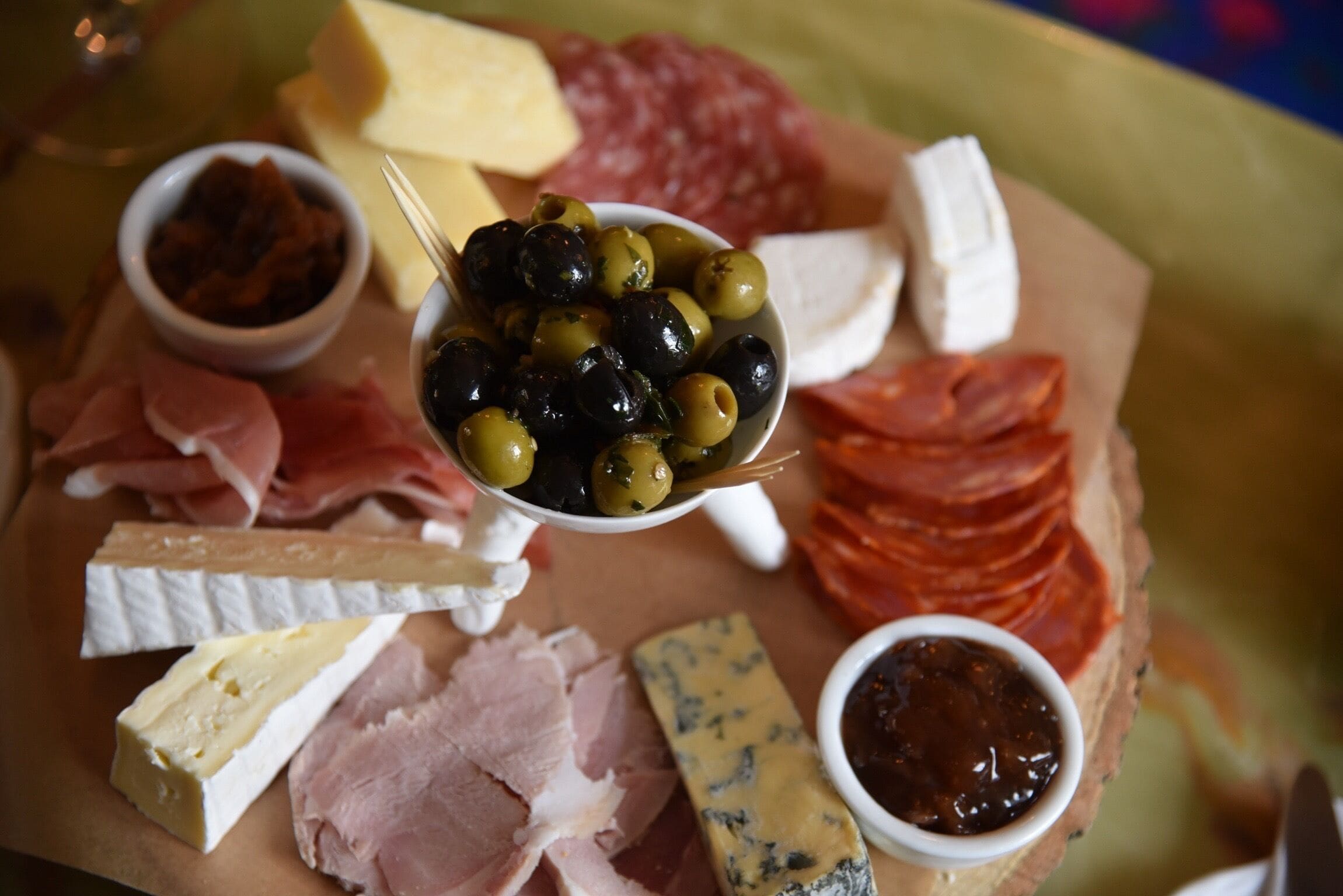 Una tabla de embutidos con quesos, carnes, aceitunas y salsas.
