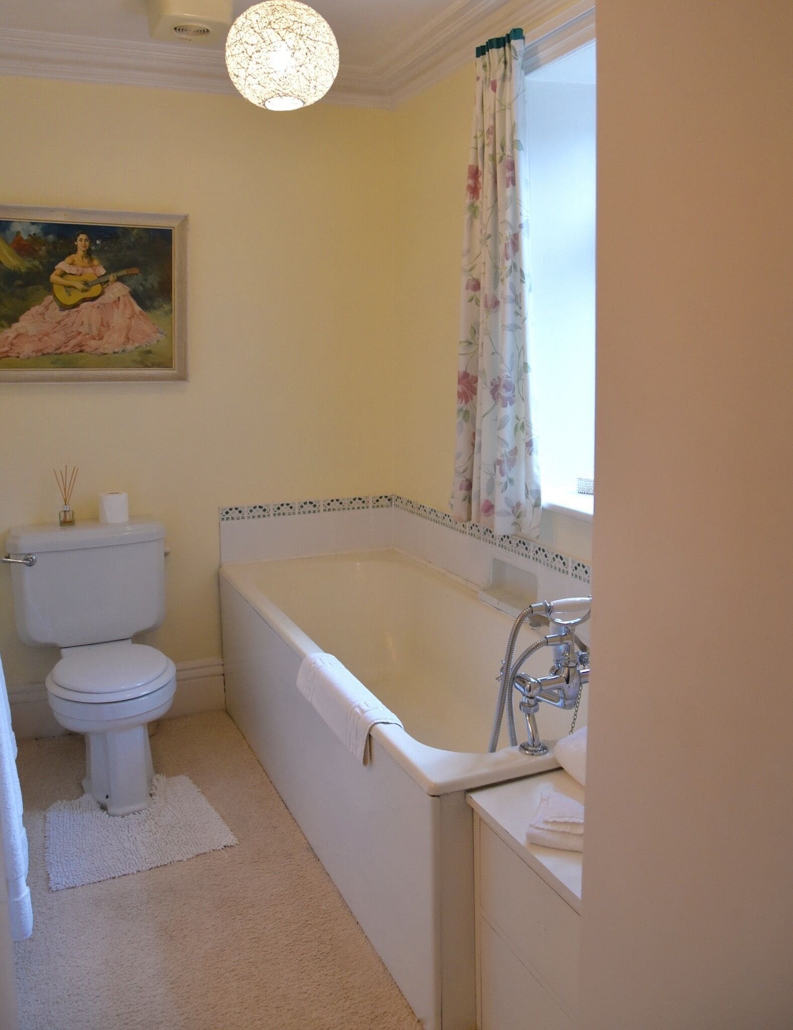 A bathroom with a bathtub, toilet, and a painting on the wall.