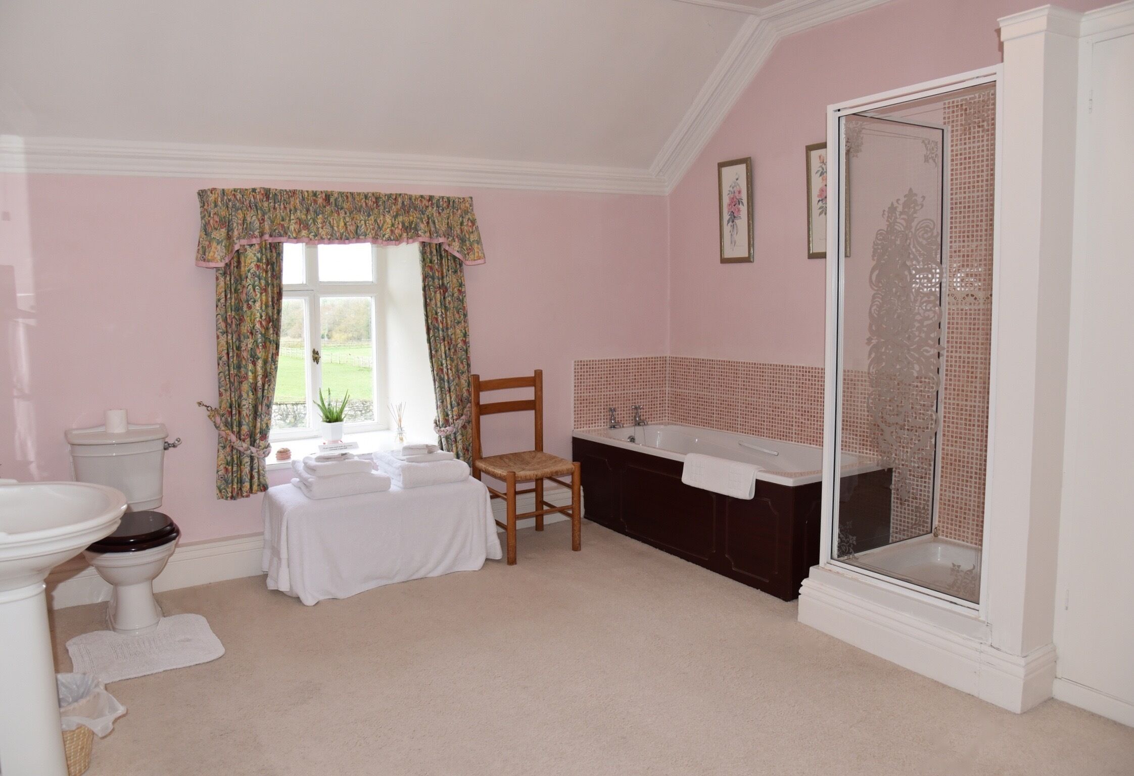 A bathroom with a toilet, sink, chair, bathtub, and shower.