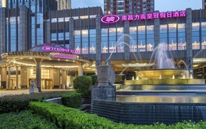 Un hotel con una fuente, un cartel que dice "CROWNE PLAZA NANCHANG RIVERSIDE" y arquitectura moderna.