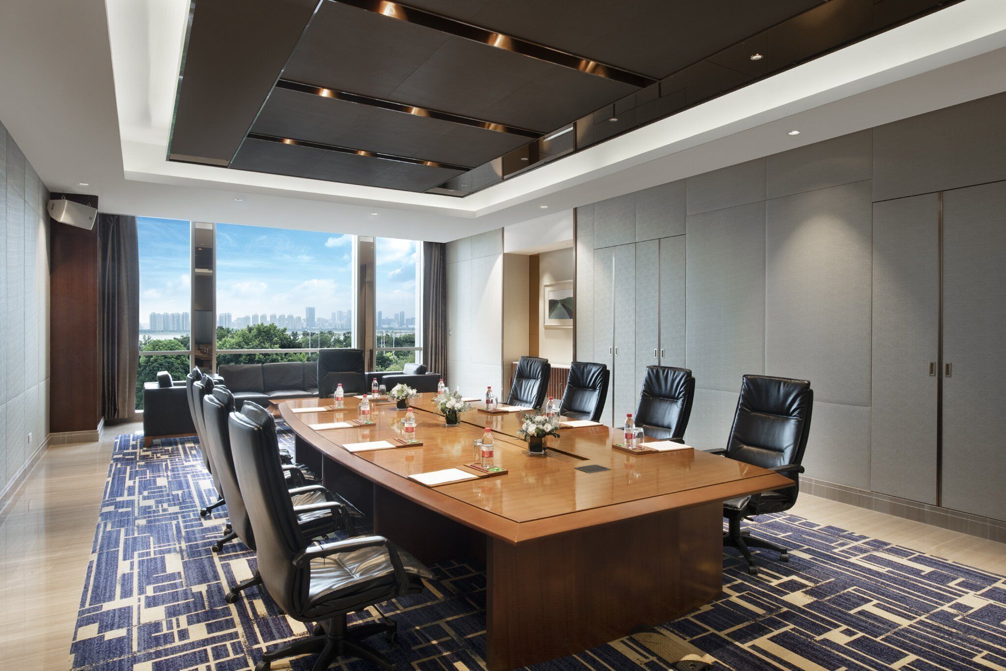 Un salón de conferencias con una mesa larga, varias sillas y vistas a la ciudad.