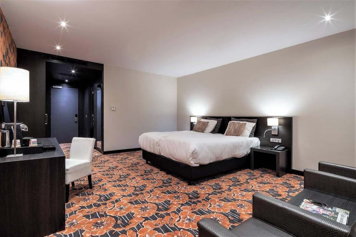 A hotel room with a bed, bedside tables, a desk, and a chair.