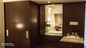 Une chambre d’hôtel avec un lit, un bureau doté d’une lampe et un miroir. Il y a une fenêtre donnant sur l’extérieur.