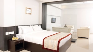 Une chambre d’hôtel moderne avec un grand lit, une table de chevet, une chaise et une cloison en verre.