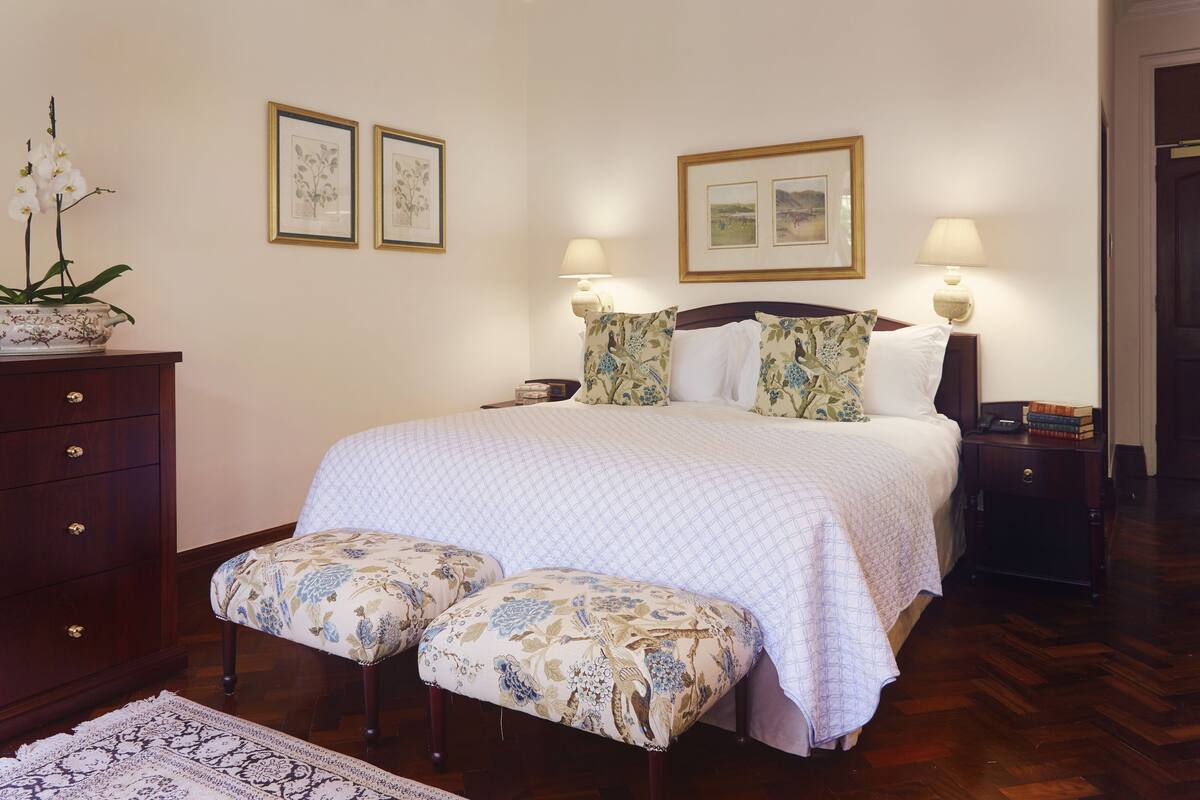 A neatly arranged bedroom with a bed, two bedside tables, a dresser, and a bench.