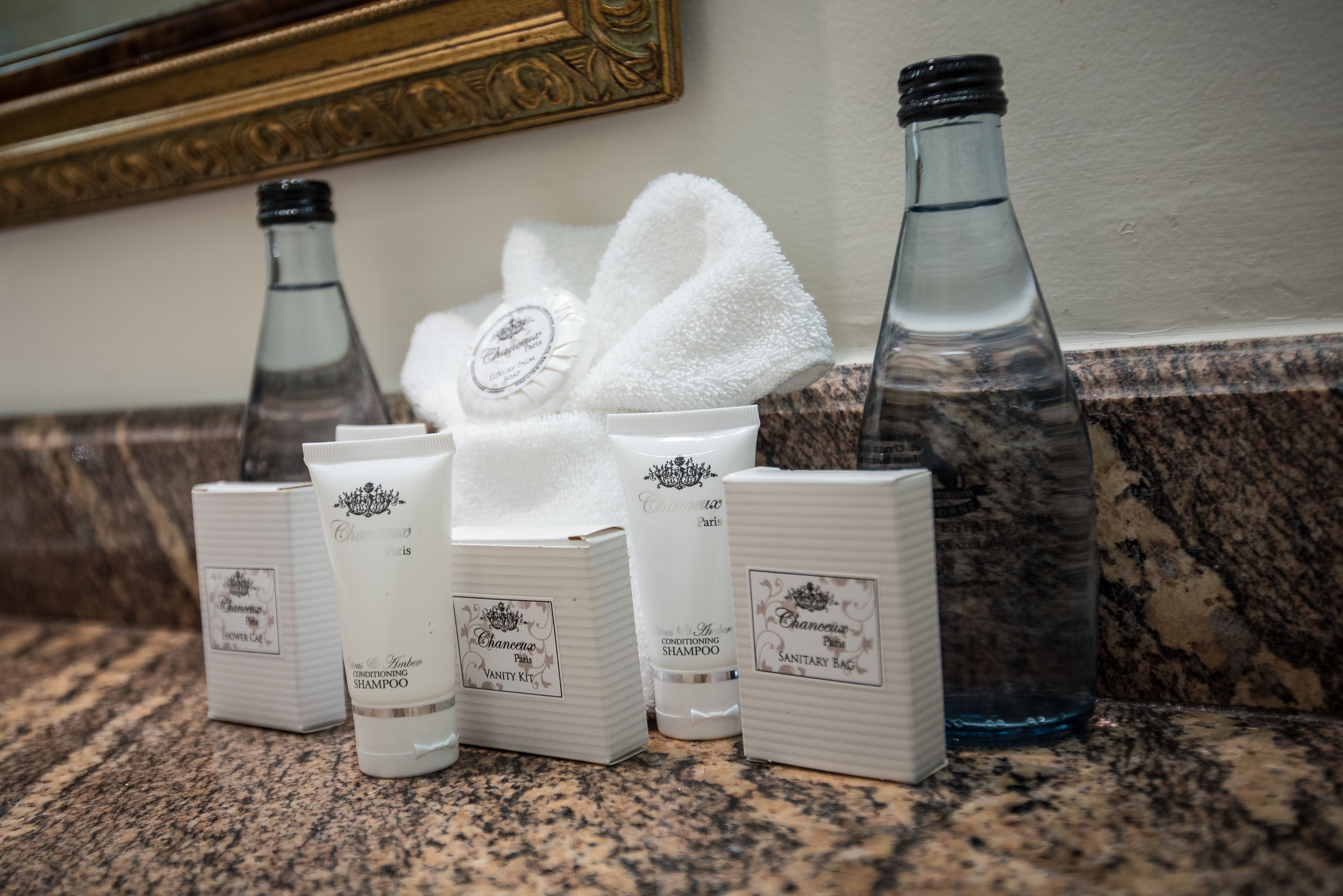 Un tocador de baño con artículos de aseo, como gorro de ducha, champú, acondicionador y una bolsa sanitaria.