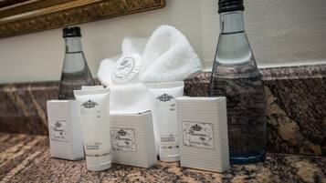 Un tocador de baño con artículos de aseo, como gorro de ducha, champú, acondicionador y una bolsa sanitaria.