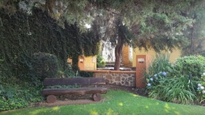 A bench in a garden with a stone wall and a tree. - Sierralta Hotel Cabañas y Convenciones (Mazamitla)