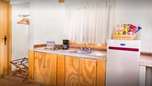A compact kitchen with wooden cabinets, a sink, a coffee maker, and a refrigerator. - Sierralta Hotel Cabañas y Convenciones (Mazamitla)