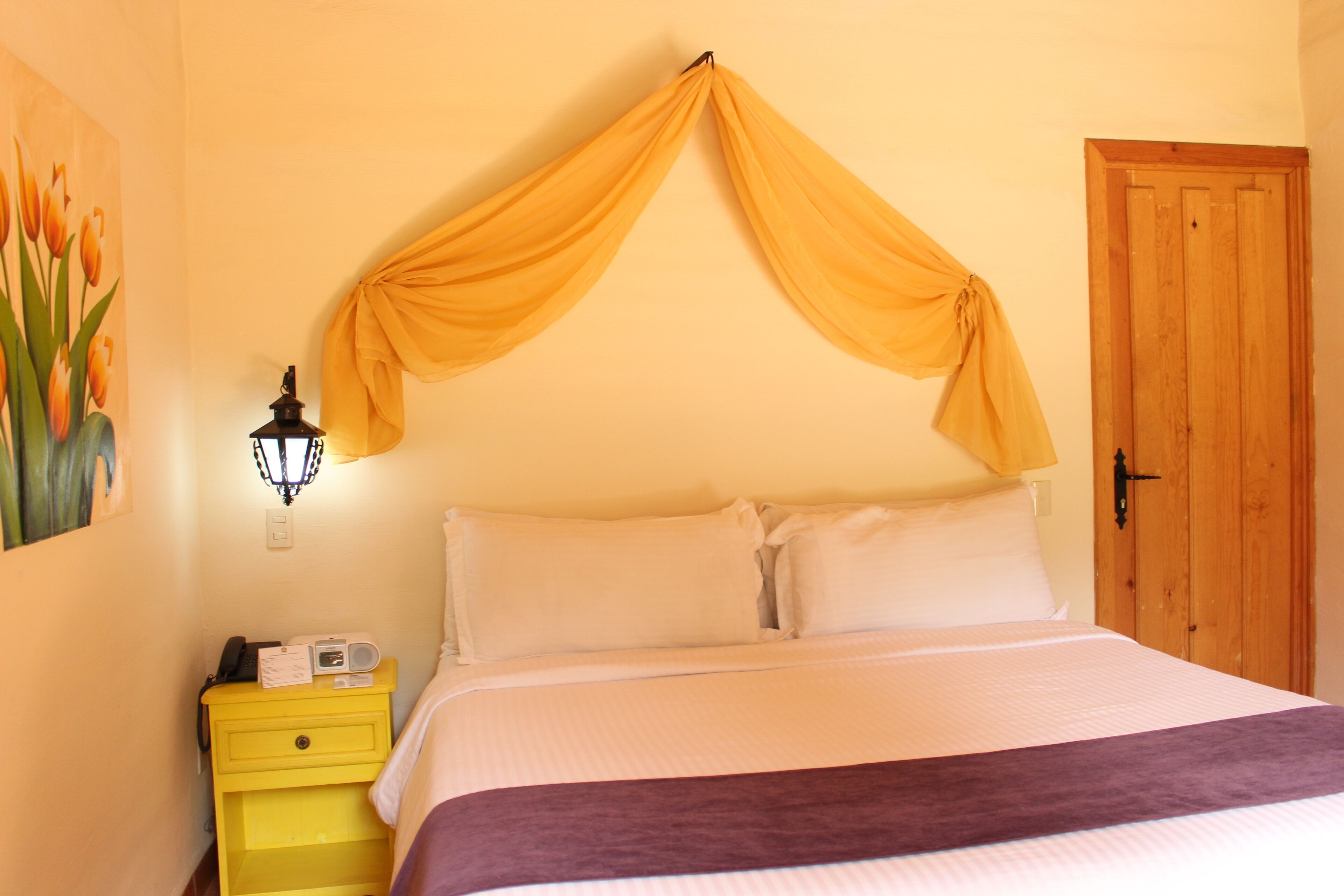 Un dormitorio con una cama, una mesita de noche, una lámpara y una puerta.