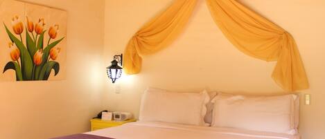 A bed with a canopy, a nightstand with a lamp, and a painting of tulips on the wall.