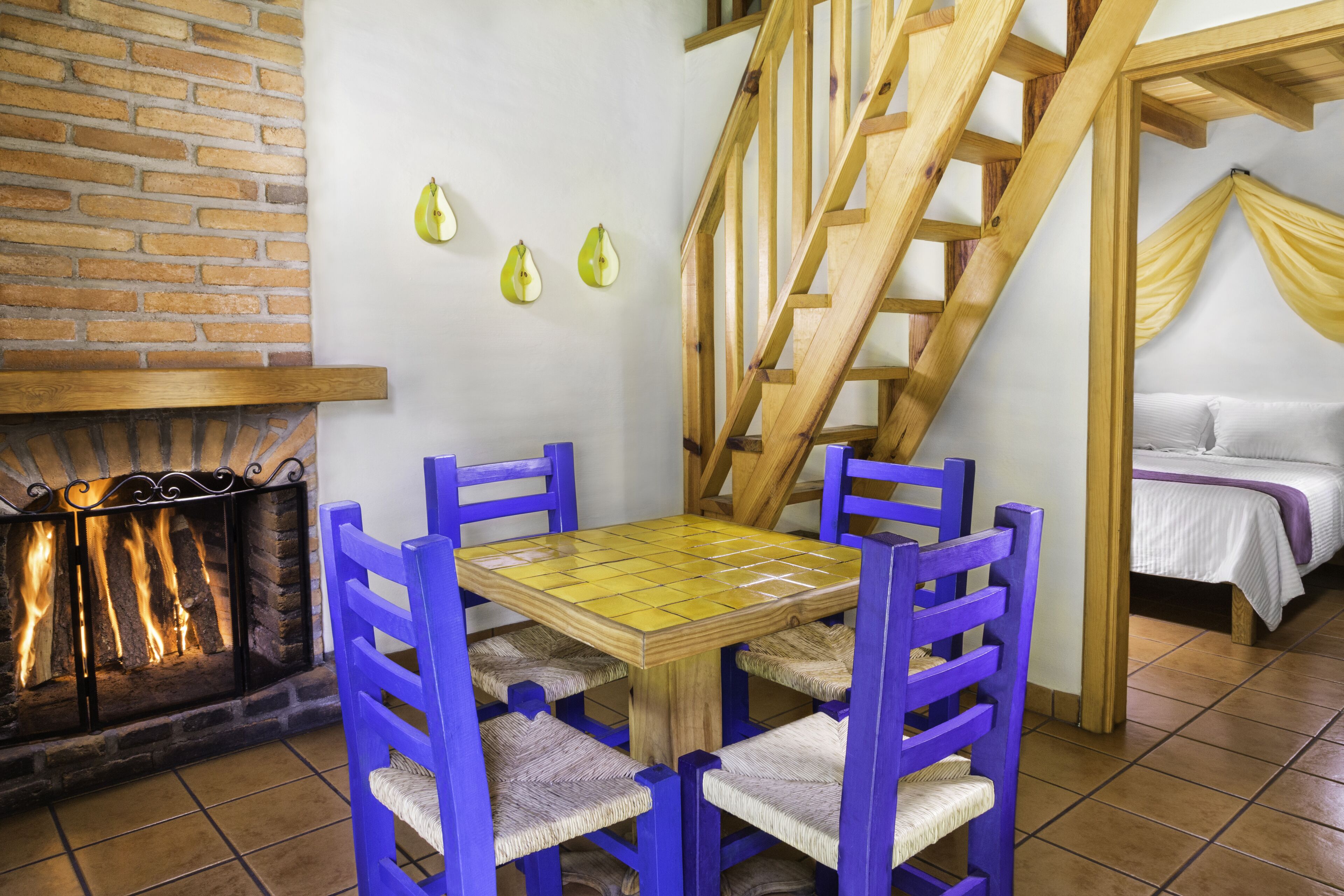 A cozy room with a fireplace, a wooden staircase, and a bed with a yellow canopy.