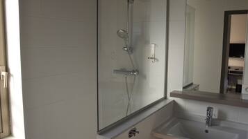 A modern bathroom with a glass-enclosed shower, a sink, and a mirror.