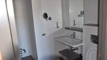 Ein modernes Badezimmer mit Waschbecken, Spiegel und Toilette in Weiß.