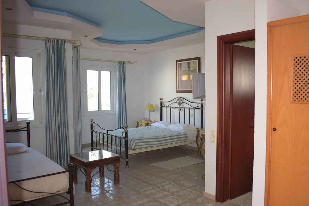 A bedroom with a bed, bedside table, lamp, and a window with curtains.