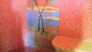 A bathroom with mosaic tile walls, a shower area, and a toilet. - Malemi Organic Hotel (Lesvos)
