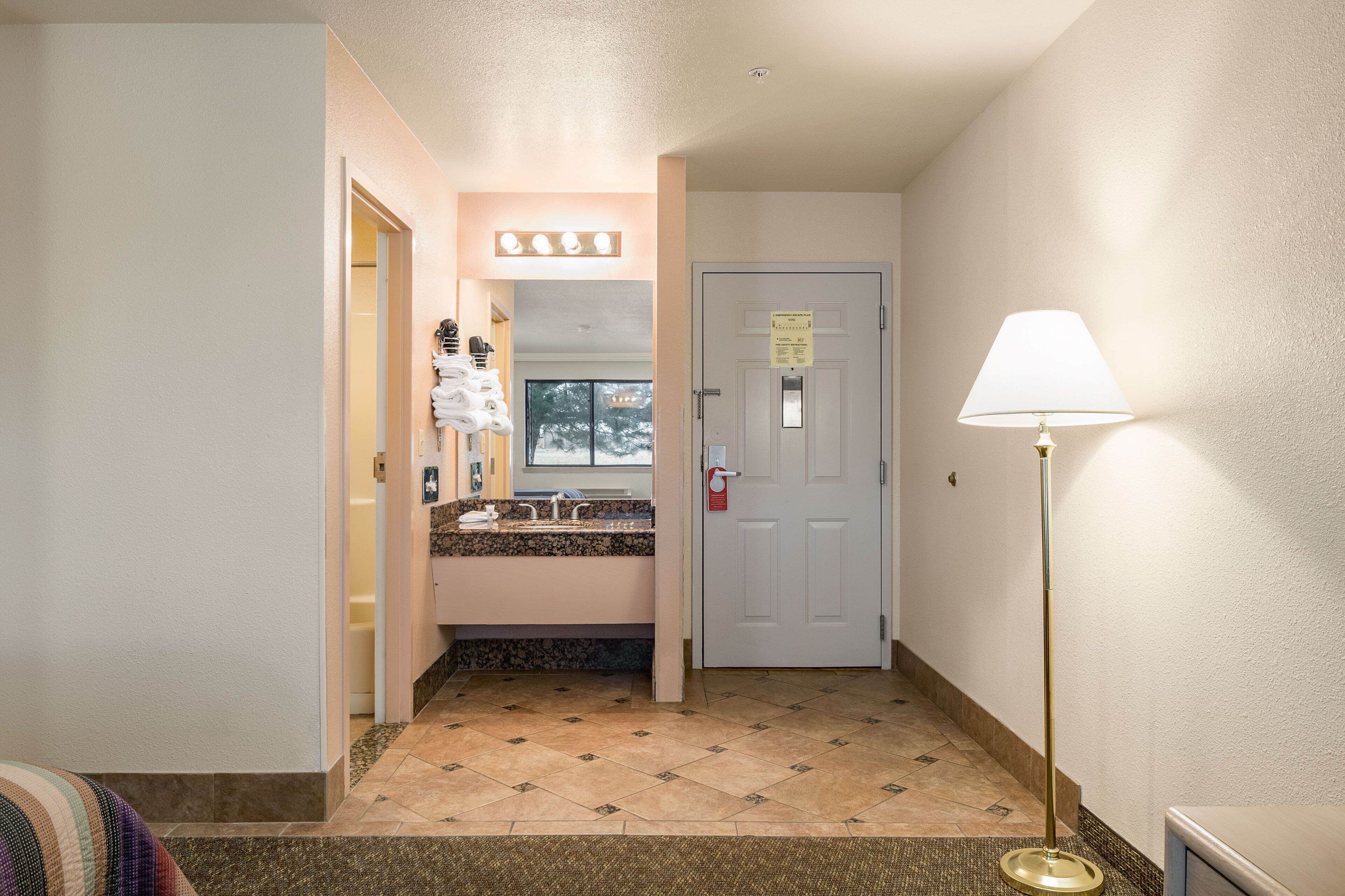 Un couloir d’hôtel avec une salle de bain, une porte avec une pancarte et un lampadaire.