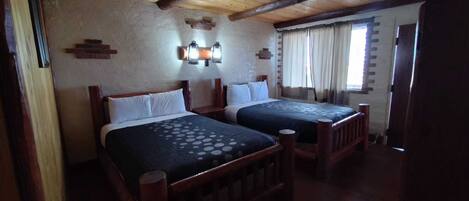 A room with two wooden beds, a brick wall, and a wooden ceiling.