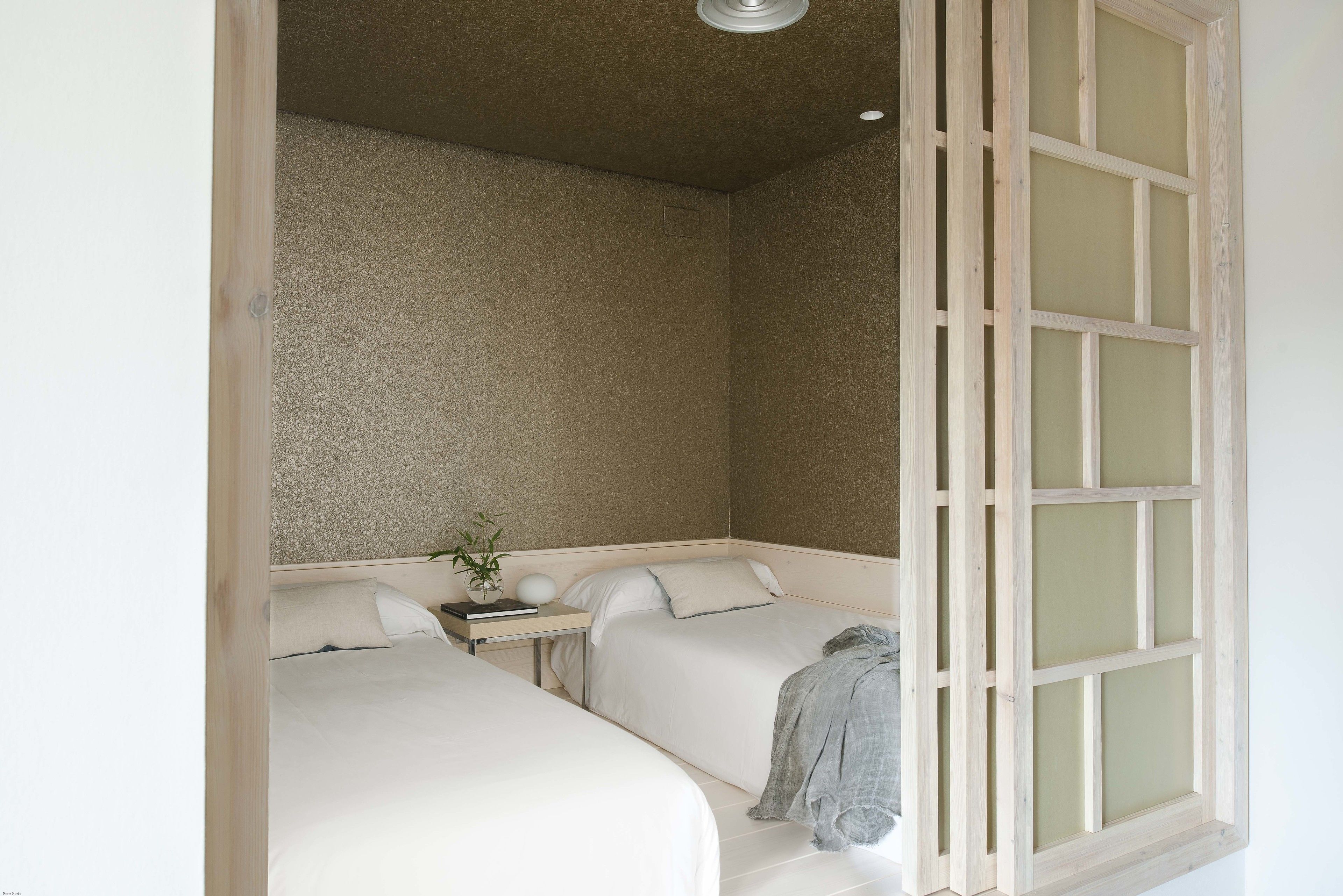 Ein Schlafzimmer mit zwei Betten, einem Nachttisch und einem Fenster mit Holzrahmen.