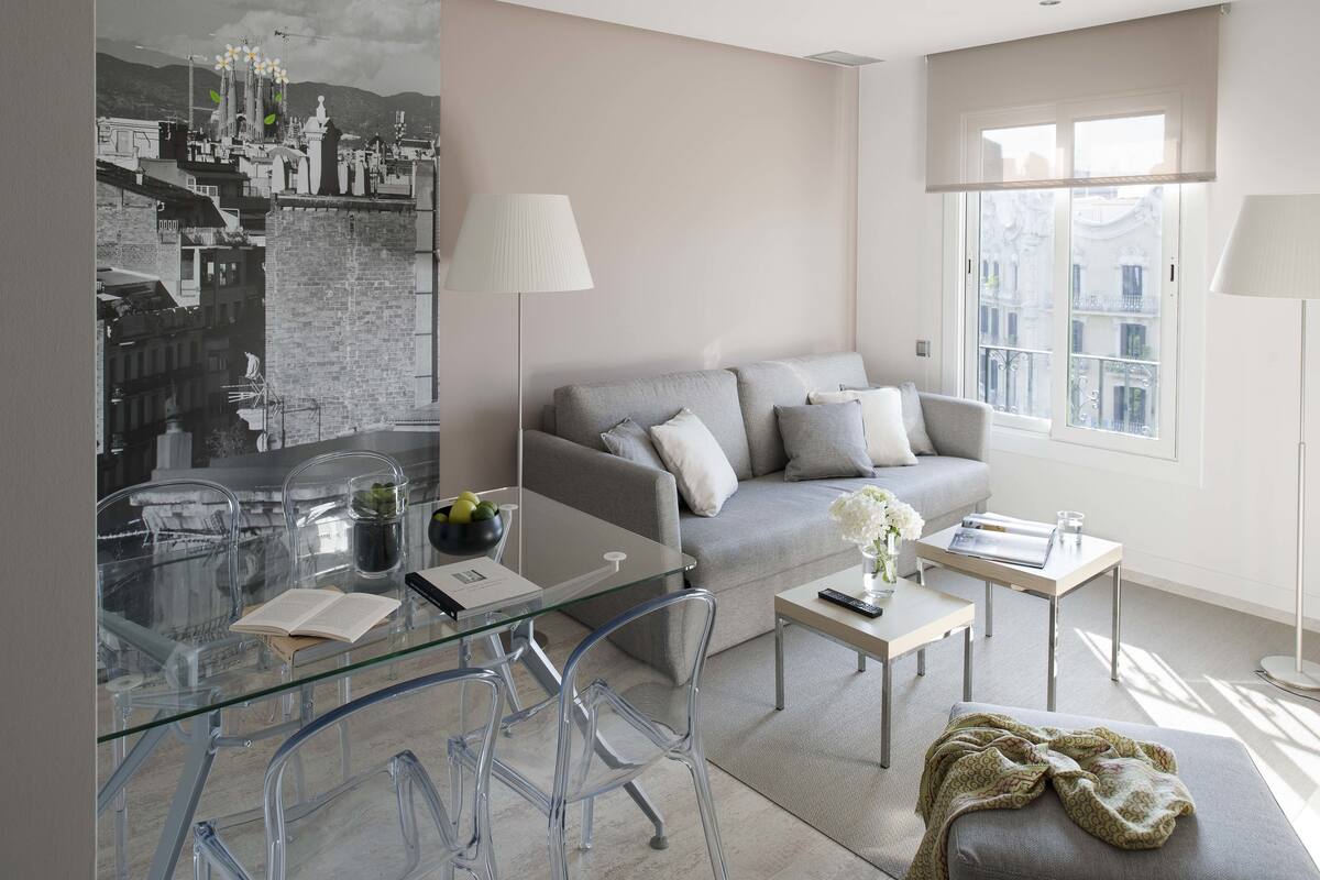 Una sala de estar moderna con un sofá, una mesa de centro y una mesa de comedor de vidrio.