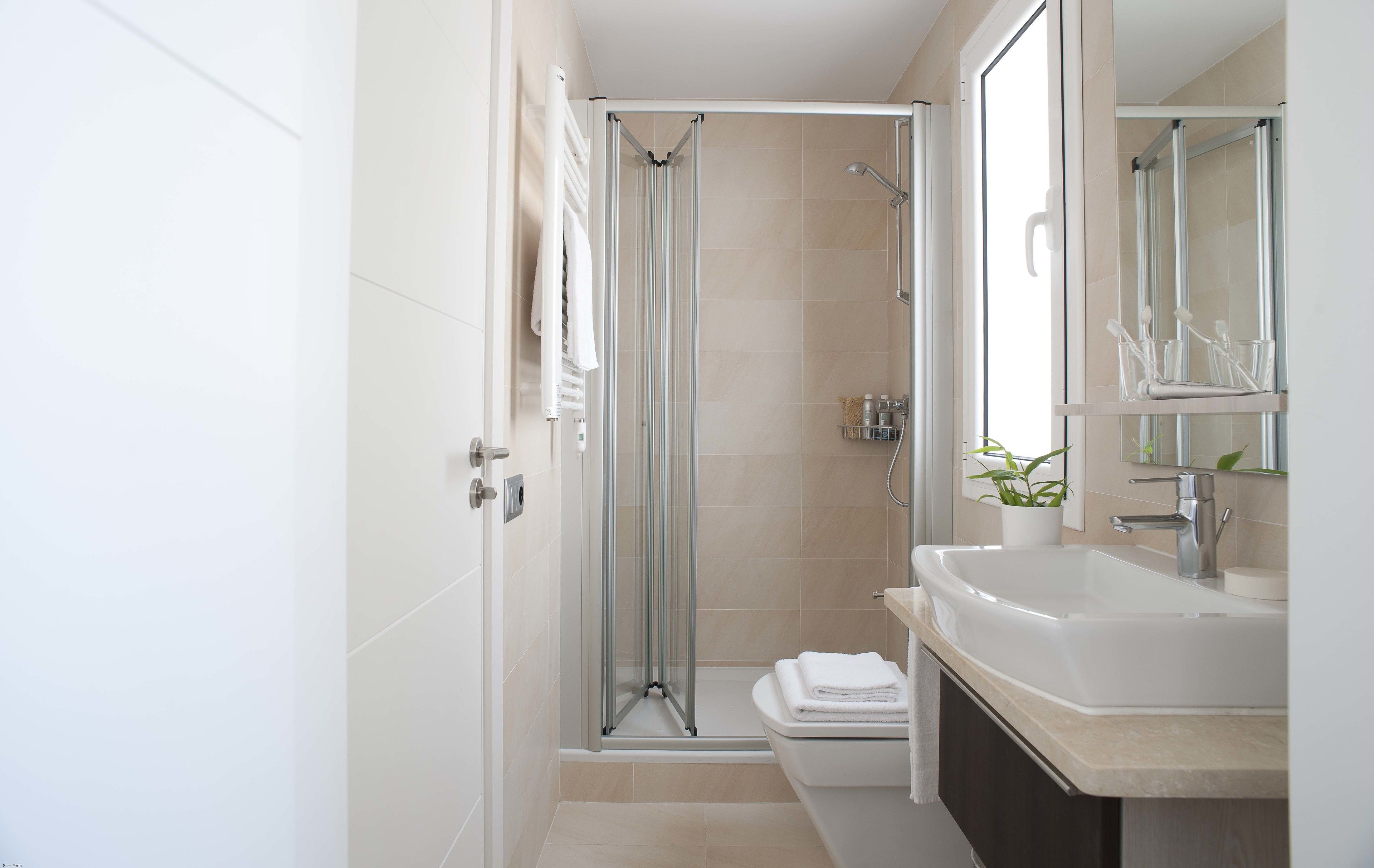 A modern bathroom with a glass-enclosed shower, a sink with a mirror, and a toilet.