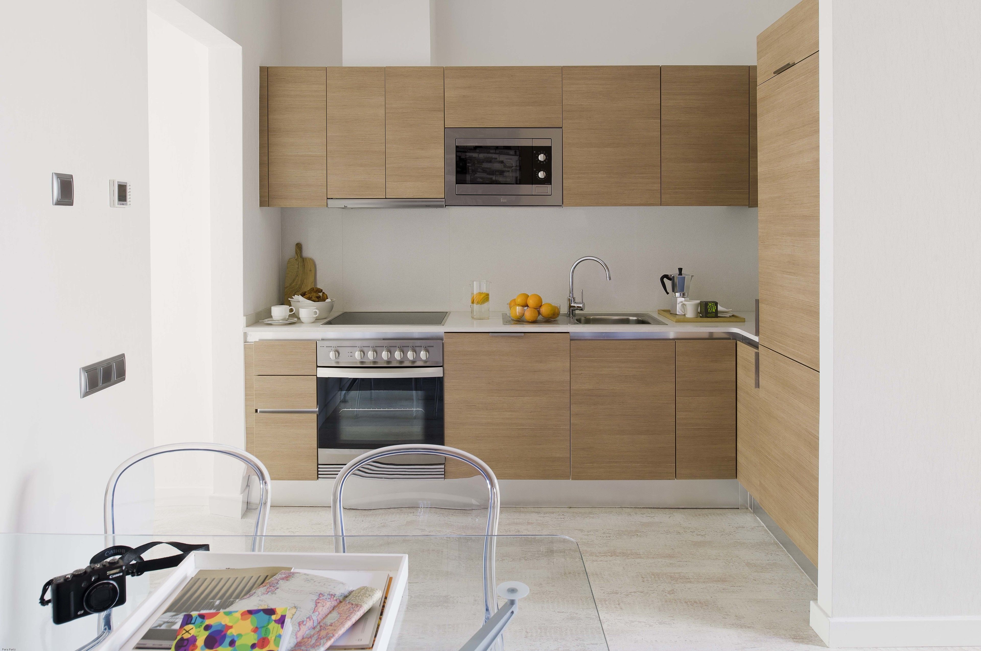 Una cocina moderna con armarios de madera, horno empotrado y microondas.