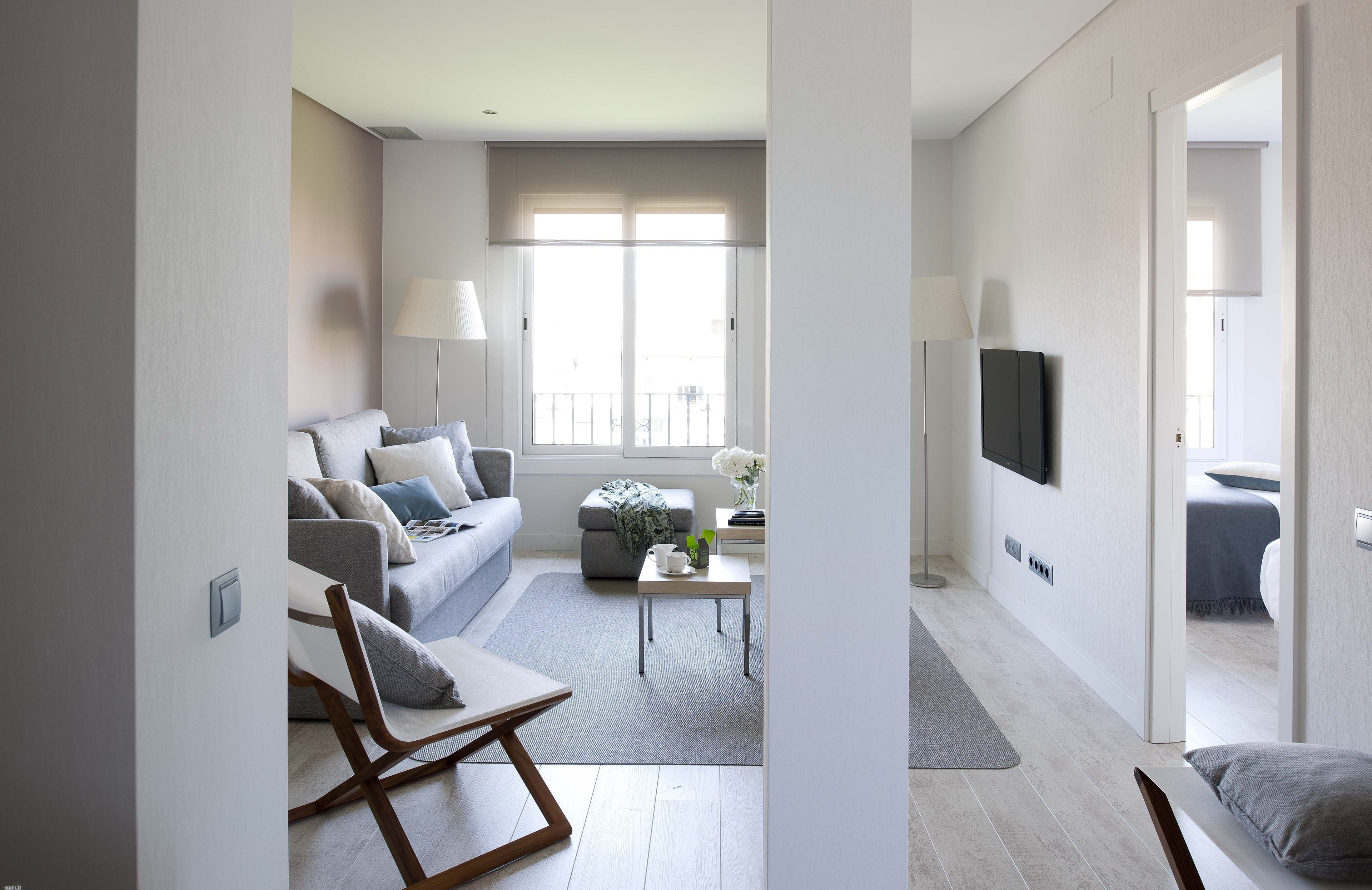 A modern living room with a grey sofa, a coffee table, and a TV mounted on the wall.