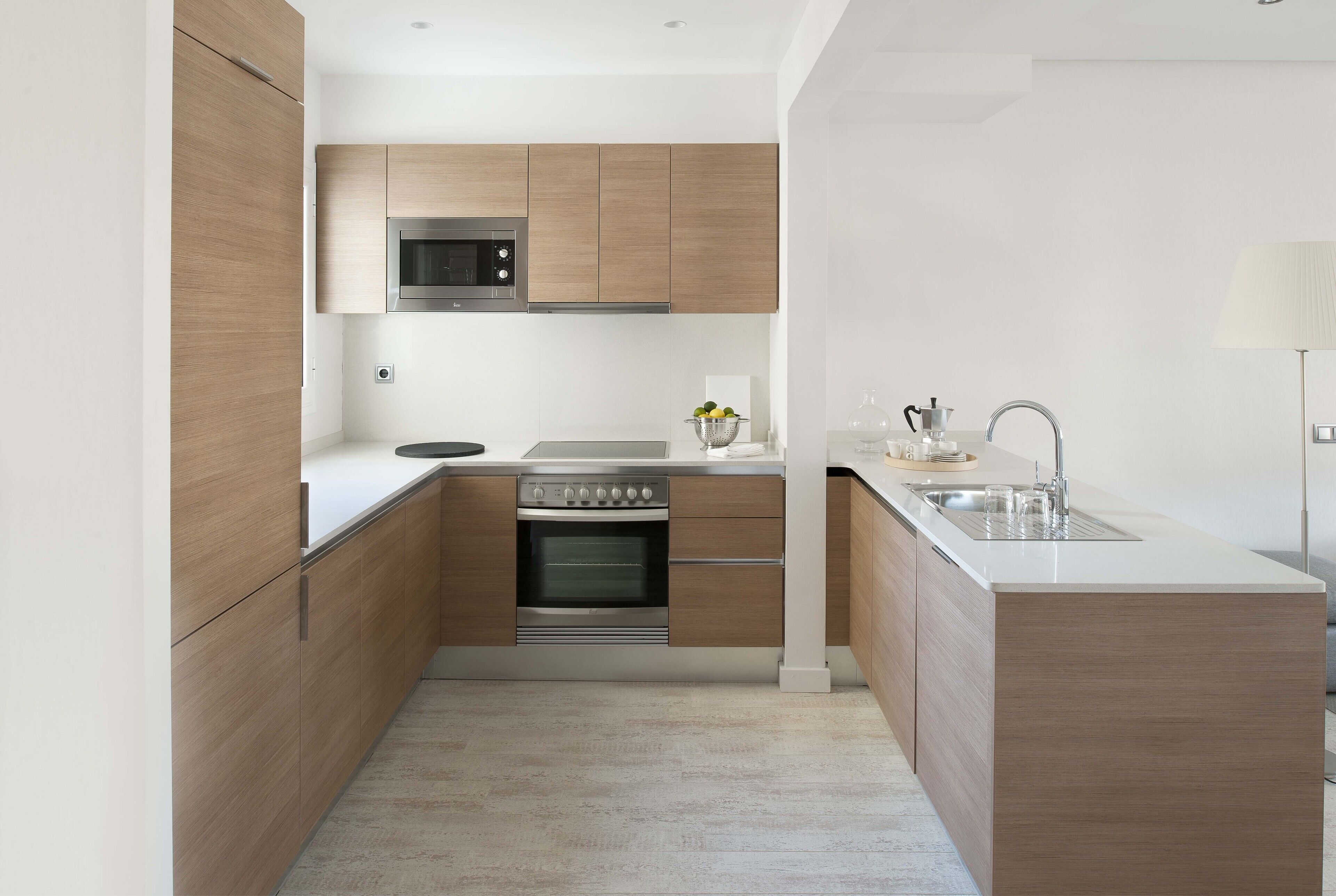 A modern kitchen with wooden cabinets, a built-in oven, a microwave, and a sink.