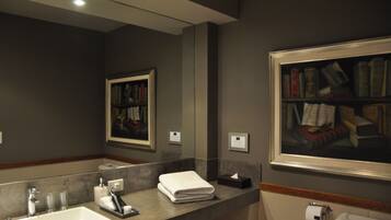 Een badkamer met een grote spiegel, een wastafel, een toilet en een lijst met een schilderij aan de muur.