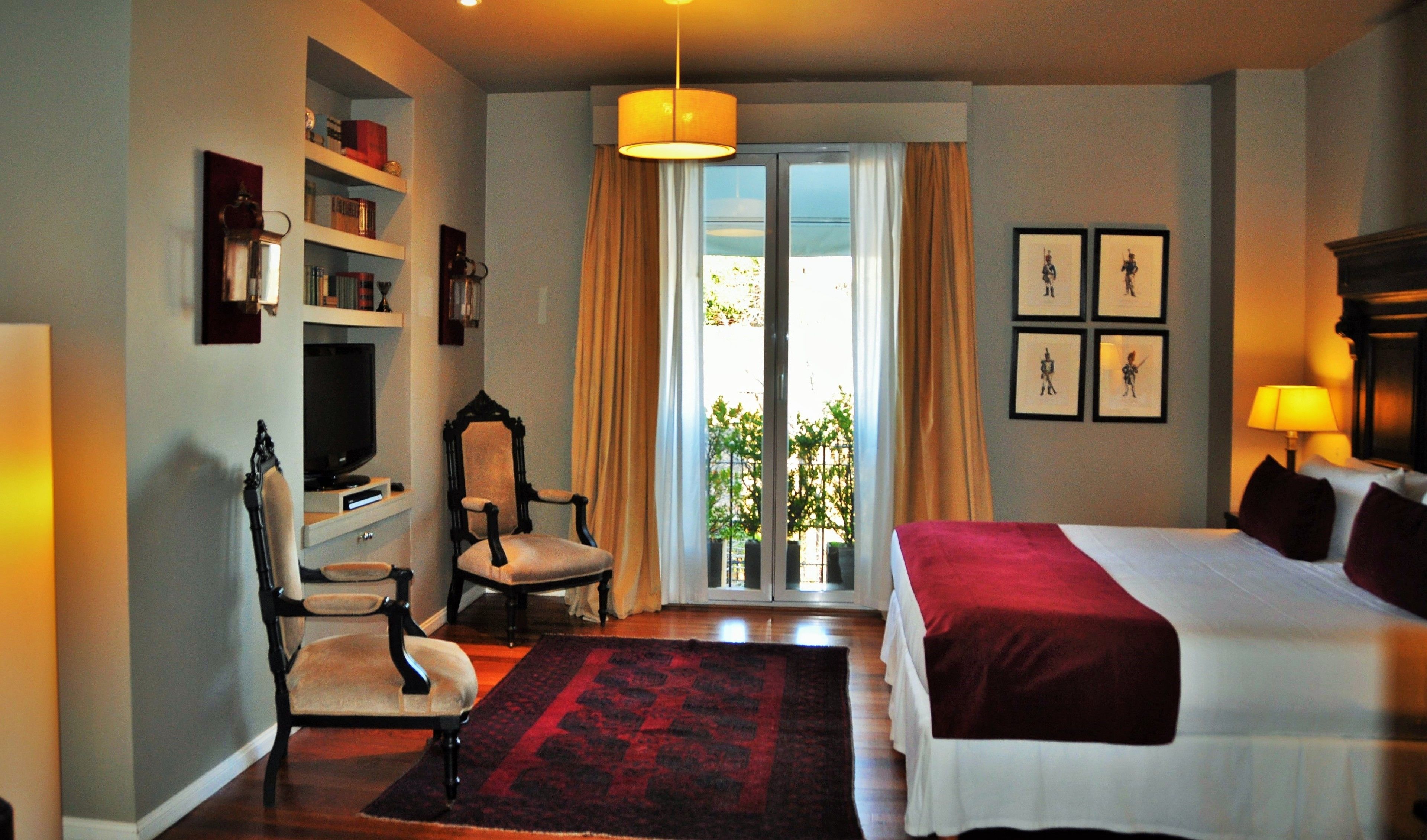 Habitación de hotel con cama, escritorio con silla, televisor y ventana con cortinas.