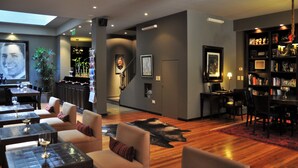 Un moderno vestíbulo de hotel con una zona de bar, asientos y una estantería.