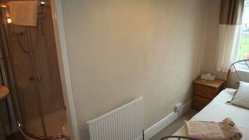A bathroom with a shower, toilet, and a radiator.