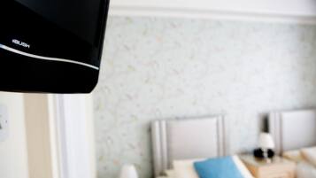 A hotel room with a bed, a nightstand, a lamp, and a wall with a floral pattern.