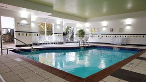 An indoor swimming pool with clear water, tiled floor, and white lounge chairs. - Fairfield Inn & Suites Flint Fenton (Fenton)
