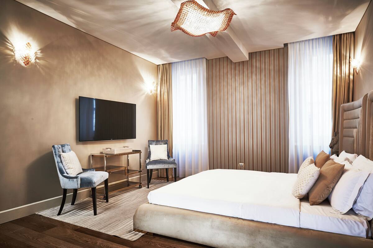 Una habitación de hotel moderna con una cama grande, un televisor de pantalla plana, un escritorio y una silla.
