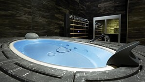 Une piscine intérieure moderne, au design en marbre noir et blanc, entourée de murs en marbre foncé.
