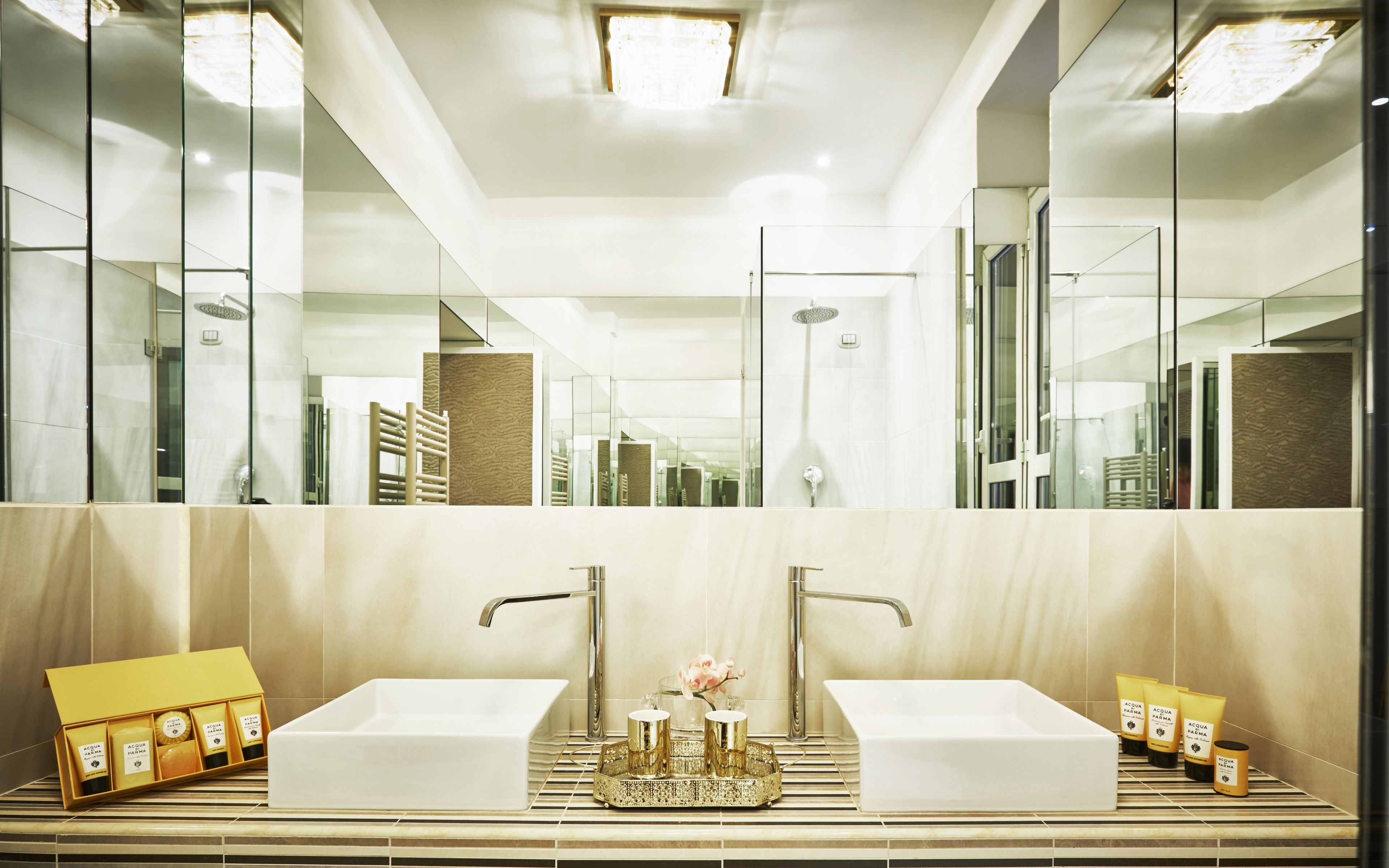 Un baño moderno con dos lavamanos, un espejo grande y una ducha.