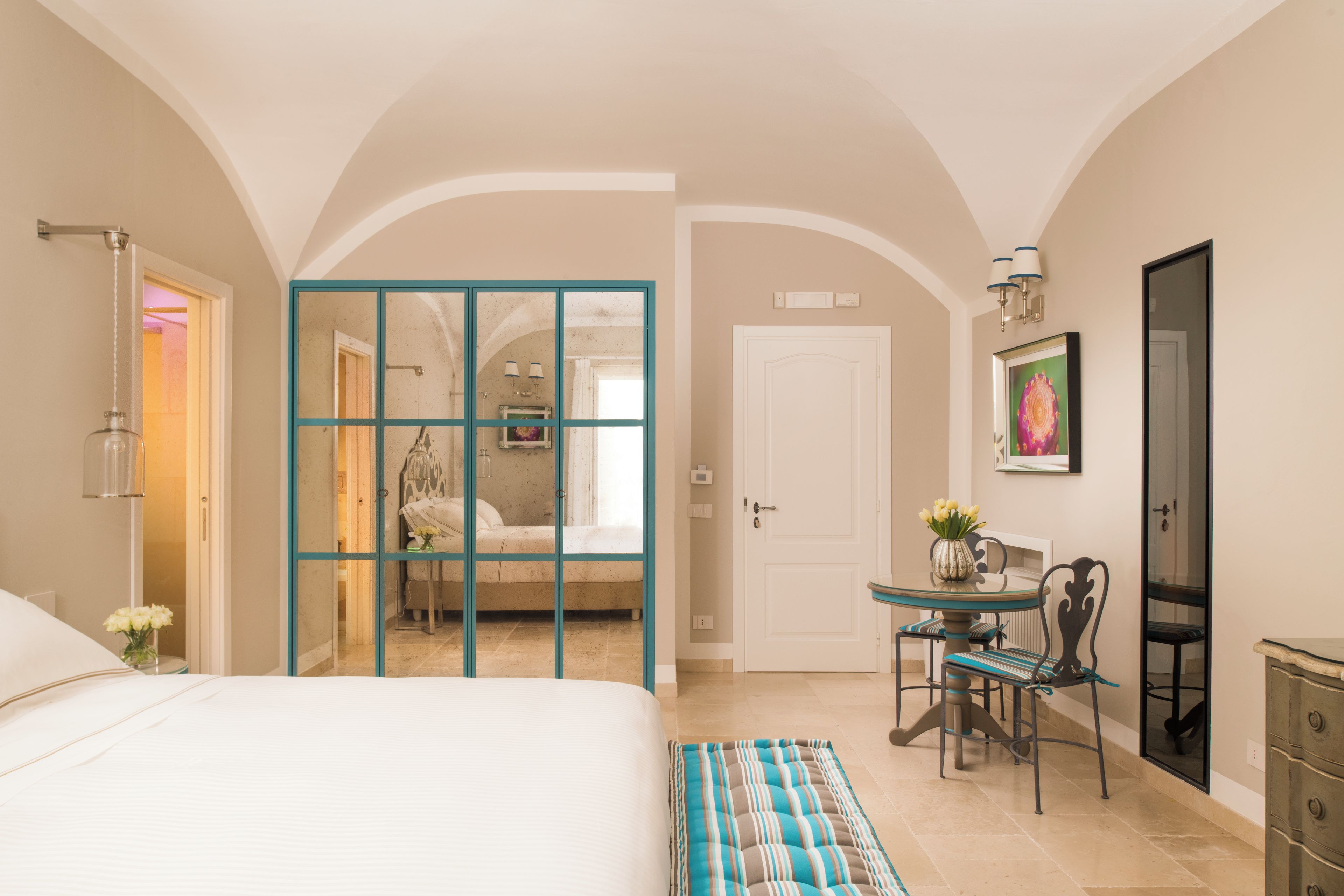 A hotel room with a bed, a desk, a chair, a dresser, a door, and a mirror.