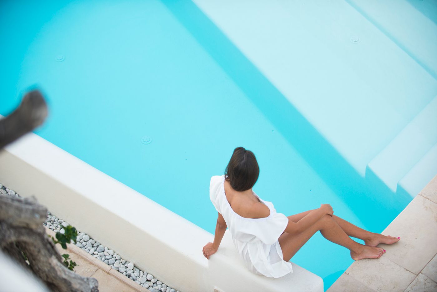 Una persona sentada junto a una piscina con vista despejada al agua.