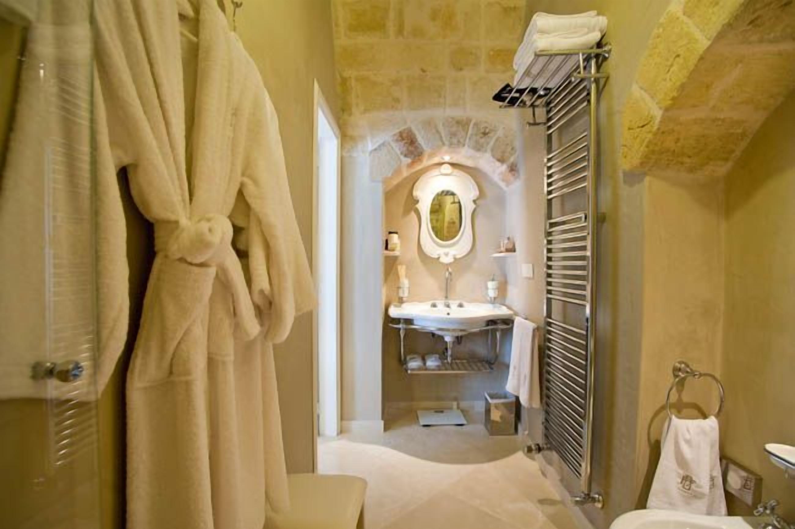 Ein Badezimmer mit Steinwand, Waschbecken mit Spiegel und Handtüchern an Wäscheständern.