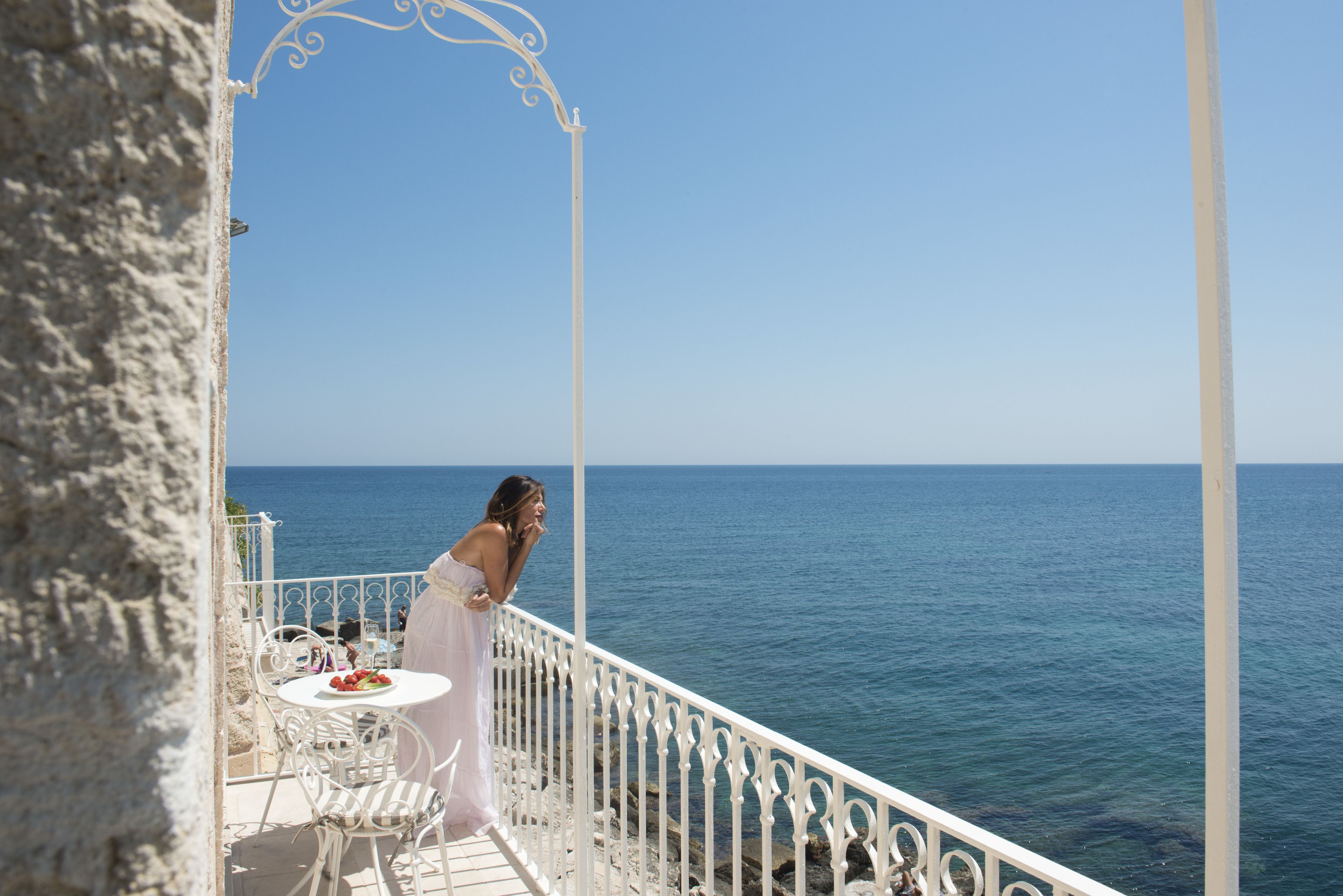 Een balkon met een witte balustrade en uitzicht op zee.