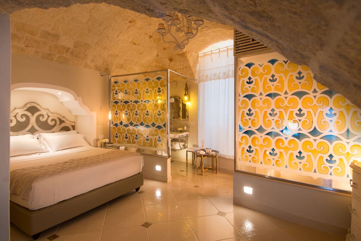 A bedroom with a large bed, a mirror, and a decorative wall.