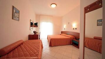 Una camera d'albergo con due letti, una scrivania, una sedia, uno specchio e una finestra con tende.