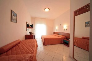 A hotel room with two beds, a desk, a chair, a mirror, and a window with curtains. - Hotel Residence Adria (Rodi Garganico)
