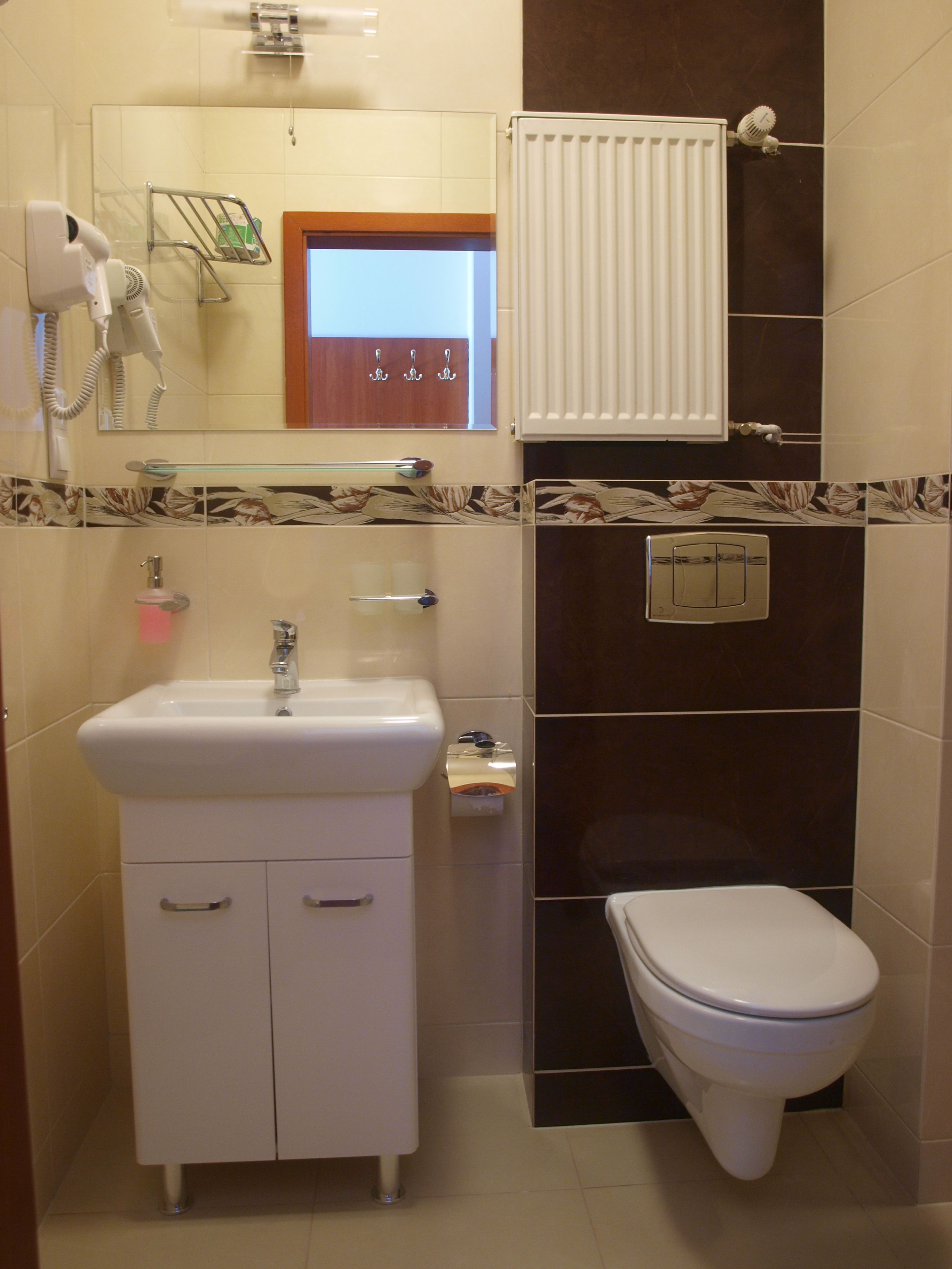Un baño con lavamanos, espejo y retrete blancos.