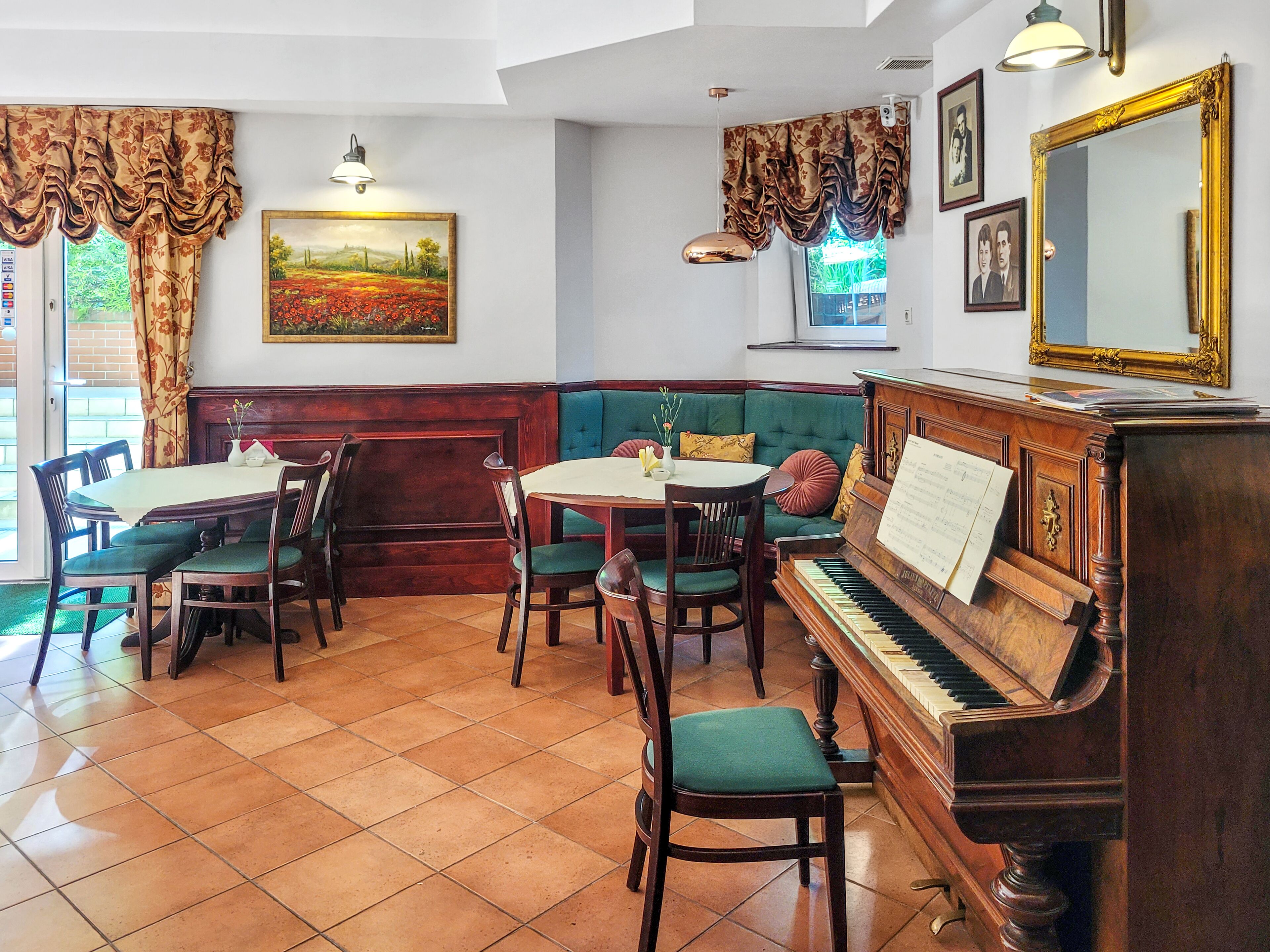 Una habitación acogedora con un piano, un sofá verde y una mesa de comedor con sillas.
