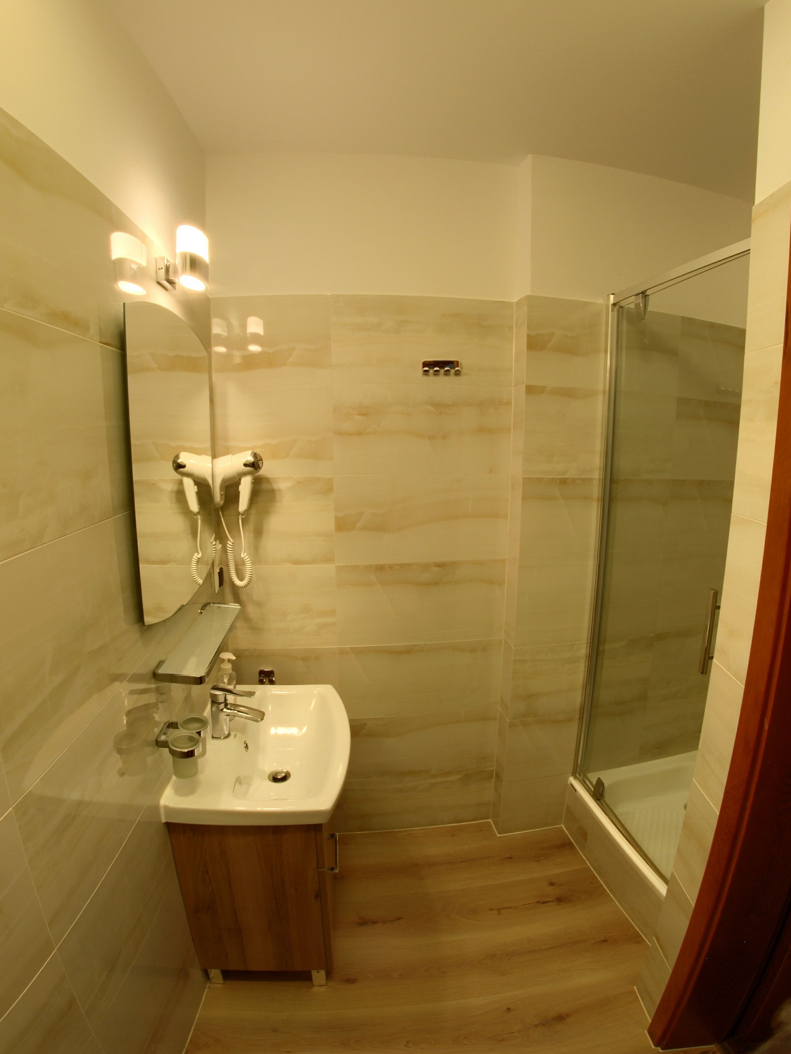 Un baño moderno con cabina de ducha de vidrio, tocador con espejo y lavabo.