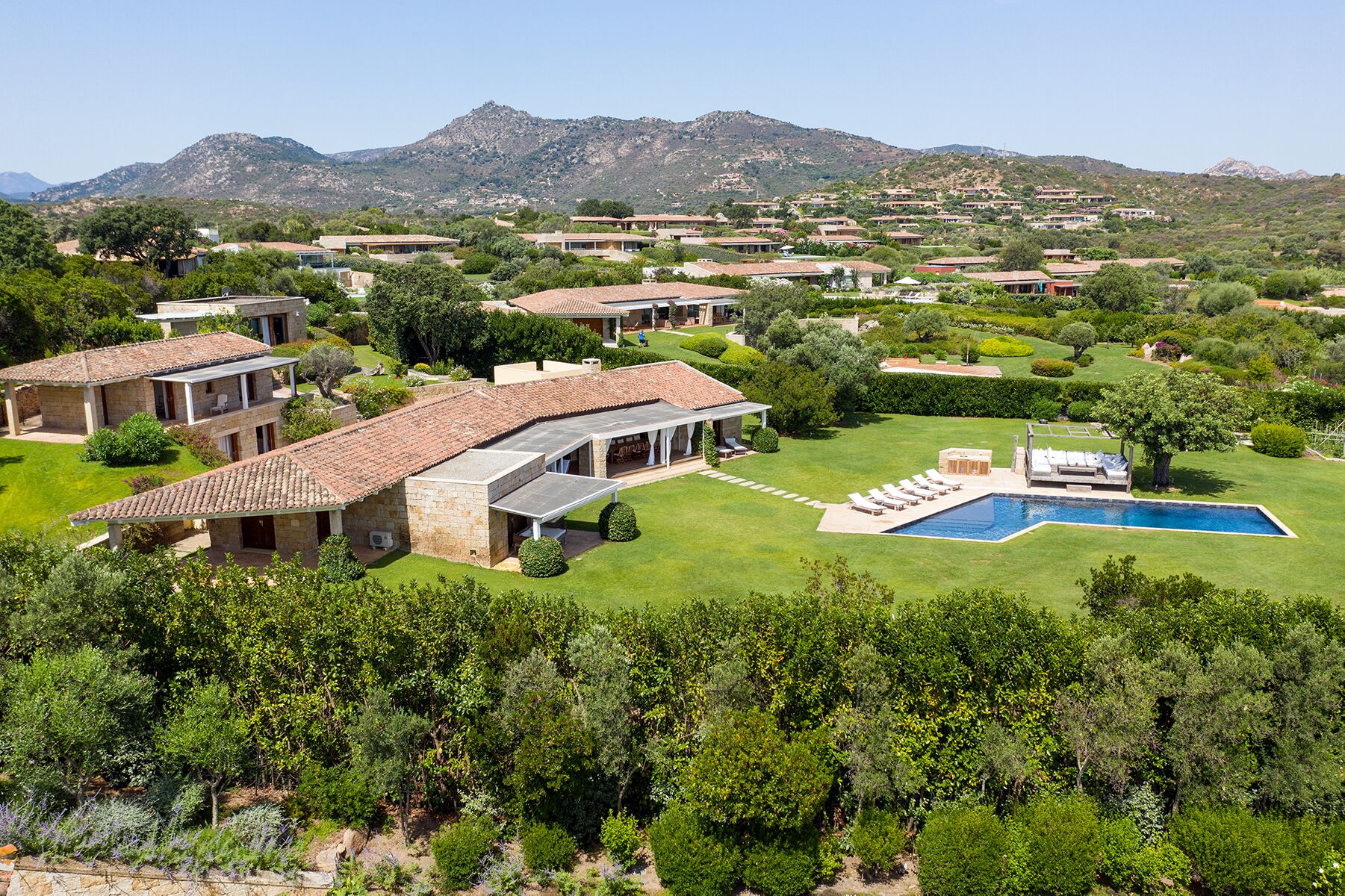Un barrio residencial con varias casas, una piscina y montañas al fondo.