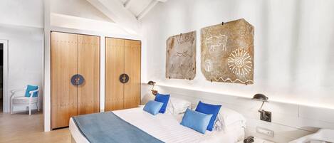 Un dormitorio moderno con una cama grande, un armario de madera y una obra de arte en la pared.